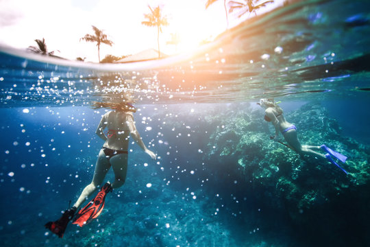 Two girls with nice butts floating in the ocean near the coral. Photo underwater