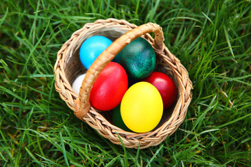 Basket with coloured Easter eggs on green grass