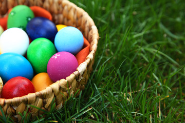 Fototapeta na wymiar Basket with coloured Easter eggs on green grass