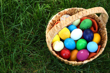 Basket with coloured Easter eggs on green grass