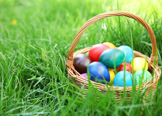 Basket with coloured Easter eggs on green grass