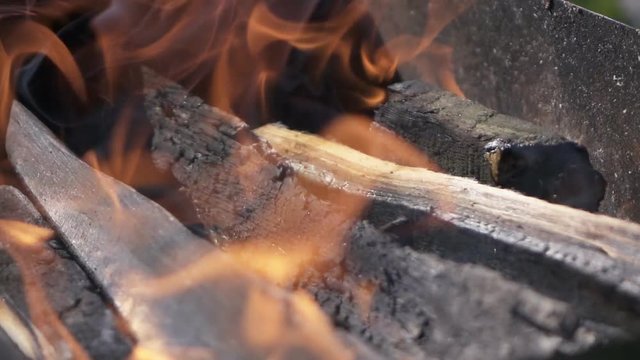 Big wooden log burning in the brazier with red flame in super slow motion. Macro high-speed camera view.