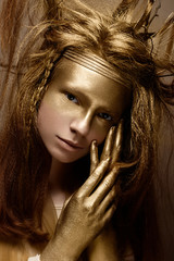 Beautiful girl in the image of a tree with branches in her hair. The model with creative make-up....