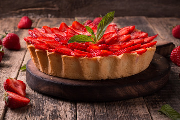 Tart with strawberries and whipped cream on wooden vintage table