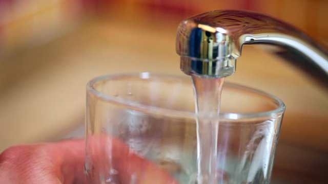 Filling up a glass of fresh water from a kitchen faucet