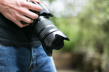 Fototapeta premium Junger Mann hält Spiegelreflexkamera in der Hand, Hüftperspektive