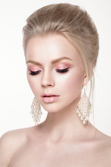 Beautiful woman portrait in tender colors. Young lady posing in studio with closed eyes and earrings in ears. Pure skin, nice make up.