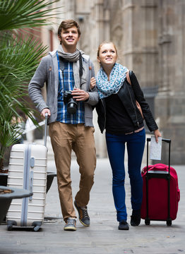 Two Travellers With Digital Camera Walking Through City Street