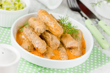 Meat finger roll in sauce from sour cream and tomato