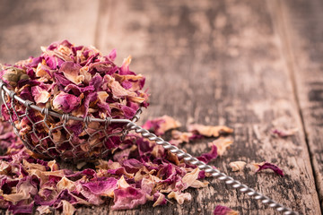 rose petals and dried flowers in spoon on old wooden table