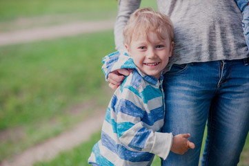 son standing next to his mother and hugs her legs