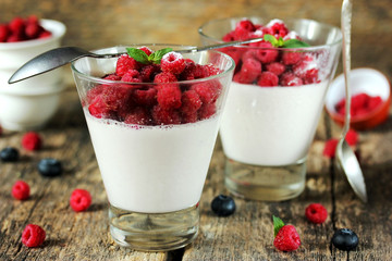 Perfect panna cotta with raspberries in glass on wooden table
