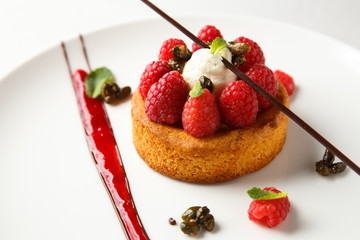 Sable breton or Breton shortbread with vanilla cream and raspberry coulis on white dish