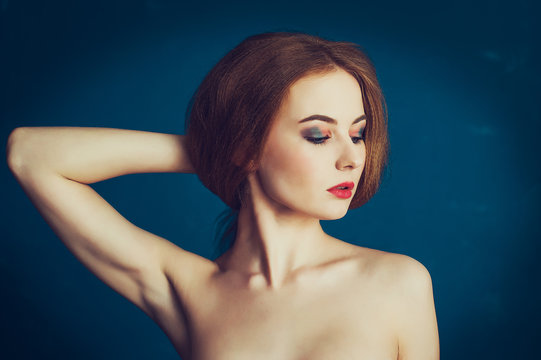 Close-up portrait beautiful woman on a blue background.  Woman showing her armpits
