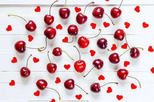 Ripe cherries scattered on a white table with hearts shapes. Che