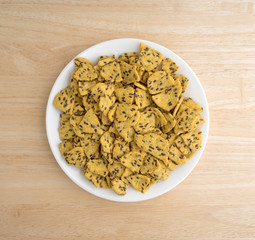 Flax seed corn chips on a white plate atop a wood table top.
