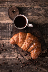 Breakfast with coffee and croissants on wooden vintage table
