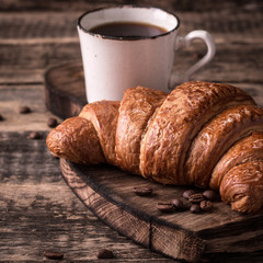 Breakfast with coffee and croissants on wooden vintage table