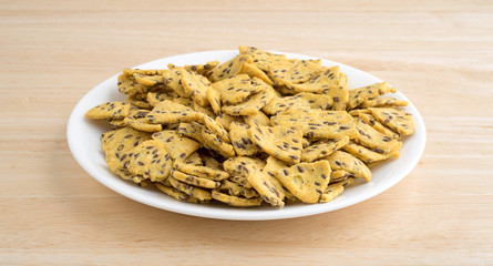 Flax seed corn chips on a white plate atop a wood table top.