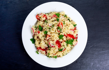 Homemade Fresh Couscous salad with vegetables, in white plate.