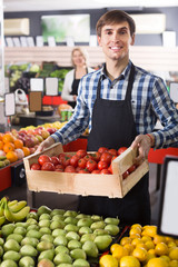 Fototapeta premium Adult employee of farm food store with fruits