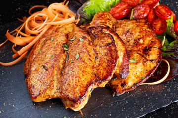 Grilled chicken breast steaks with cherry tomatoes, carrots, salad leaves.