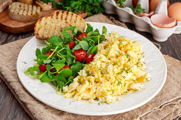 Scrambled eggs on plate with vegetables and grilled toast.