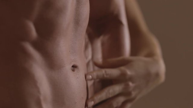 Hands of young woman touching athletic torso with abs of man. Ungraded