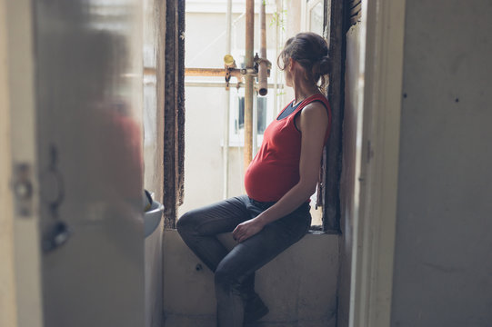 Pregnant woman sitting by window in house being renovated