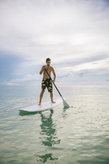 Man stand up on paddle board at sunset