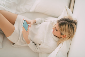 Obraz na płótnie Canvas Girl Using Smart Phone In Bed