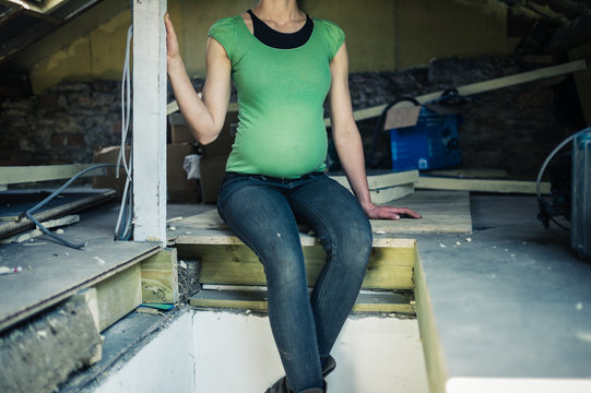 Pregnant woman sitting in attic