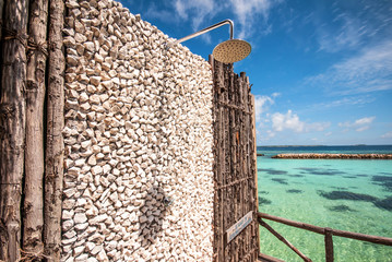 Outdoors shower with stoned wall with view to blue lagoon