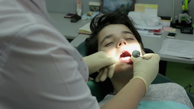 Orthodontist at work. The boy at a visit at the dentist. Inspection of the bite of the guy.