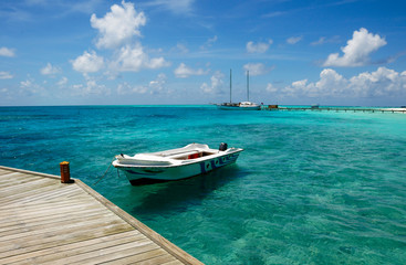 Naklejka na ściany i meble Moored white boat in blue Maldivian lagoon