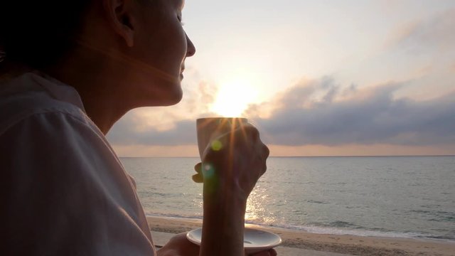 Woman Taking a Sip of Coffee in Beach Restaurant by Sea