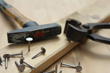 Hammer, pliers and metallic nails. Nail head in focus. Carpentry works. 