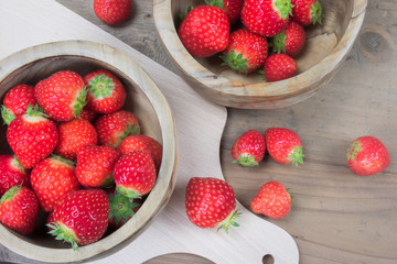 Strawberries/ Cooking concept with juicy and healthy strawberries in wooden bowl, cutting board and wood background.