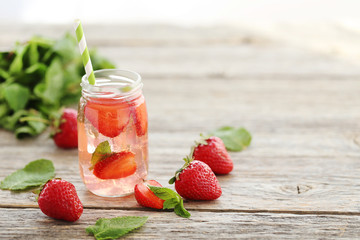 Fresh strawberry drink in bottle on wooden table