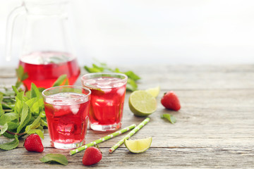 Fresh strawberry drink in glass with lime on wooden table