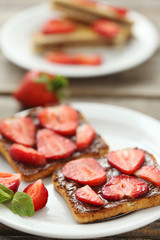 French toasts with chocolate and strawberry on wooden table