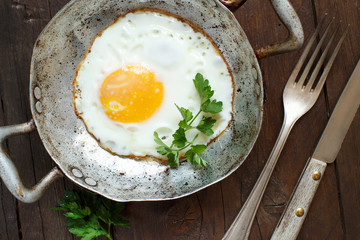Fried egg with tomatoes and herbs n a old frying pan