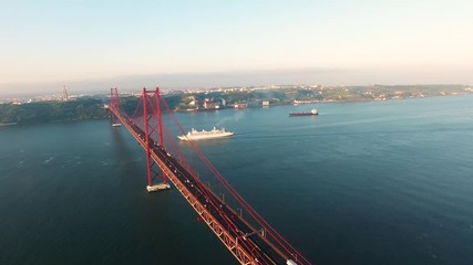 cruise ship under Bridge Ponte 25 de Abril over the Tagus river in Lisbon, Portugal aerial view