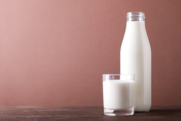 bottle and glass of milk on a chocolate background