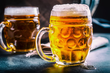 Beer. Two cold beers. Draft beer. Draft ale. Golden beer. Golden ale. Two gold beer with froth on top. Draft cold beer in glass jars in pub hotel or restaurant. Still life.