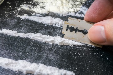 Man is making lines of cocaine white powder for snorting.