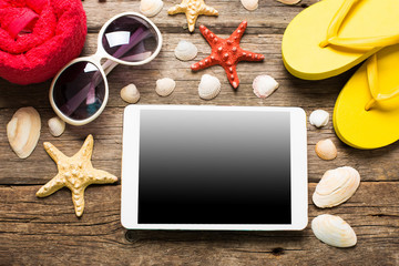 Summer women's accessories: red step-ins, denim shorts, tablet, camera, sunglasses on  wood background.
