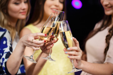 Clinking glasses of champagne in hands on bright lights backgrou