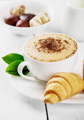 Hot cappuccino and pastries on white wooden boards