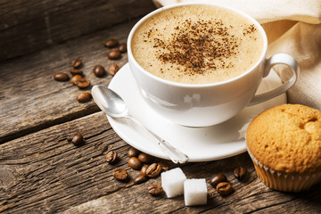 Close-up of coffee cup with roasted coffee beans on wooden backg